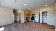 This well-designed single-floor unit offers a clean, contemporary aesthetic throughout. The open-concept layout seamlessly connects the kitchen and living area, creating a spacious and functional flow. The kitchen is outfitted with light wood cabinetry, stainless steel appliances including a French door refrigerator with ice maker, electric range, built-in microwave, and dishwasher, all complemented by neutral countertops and a stainless steel sink. Recessed lighting illuminates the kitchen and main living space, which features warm hardwood-style flooring that extends throughout.

The living area is generously proportioned, with warm-toned walls and a row of windows that allow natural light to fill the room. A separate bedroom includes a sliding glass door that opens to an outdoor view of the surrounding neighborhood, along with a ceiling fan and ample closet space. An additional bedroom provides a quiet retreat with its own closet access.

The bathroom is finished with large-format tile flooring, a single-sink vanity with cabinetry, a mirror, and overhead lighting. A walk-in closet is also present, offering convenient storage. Throughout the unit, the design emphasizes clean lines, neutral tones, and practical finishes that create a comfortable and move-in-ready living environment.