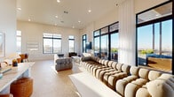 Located at 1492 E Jefferson Blvd in Dallas, TX, this single-floor communal space offers a sophisticated and airy environment defined by clean modern design and an abundance of natural light. The layout encompasses two distinct functional areas that flow cohesively together across a generous open floor plan finished with polished terrazzo-style flooring throughout.

The lounge area is a standout feature, anchored by expansive floor-to-ceiling black-framed windows and glass doors that frame sweeping views of the Dallas skyline and surrounding cityscape. Dramatic sheer white curtains line the glazed walls, softening the light while maintaining the open, elevated feel. Sculptural, tufted modular sofas in neutral tones are arranged to encourage gathering, complemented by a sleek white coffee table and accent seating. The space opens directly onto an outdoor terrace, extending the lounge experience outdoors.

The dining area transitions seamlessly from the lounge and features a distinctive design palette — a soft gradient mural wall in blue and warm peach tones sets a creative backdrop above terracotta tile accents and white cabinetry with a built-in sink. Two round dining tables with dark bases are paired with warm cognac leather chairs beneath an elegant linear pendant light, creating an inviting setting for shared meals or meetings. A wall-mounted display screen and tall cabinetry add functional versatility to this thoughtfully designed communal space.