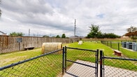 Located at 19221 Beechnut St in Richmond, TX, this outdoor dog park — known as Bark Park — offers a generously sized, open-air recreational space designed specifically for pets and their owners. The grounds are covered in lush green grass and are enclosed by a tall wooden privacy fence along the perimeter, providing a secure and contained environment for dogs to roam freely. A black metal fence section runs along one side, offering visibility to the surrounding neighborhood while maintaining safety. The park features a variety of amenities, including agility equipment, benches for owners, and a decorative log-style structure that serves as an interactive play element for dogs. A mature shade tree stands prominently in the space, offering relief from the Texas sun. A stacked stone feature adds a natural, landscaped aesthetic to the grounds. Waste disposal stations are conveniently positioned throughout the area. Clearly posted rules and signage at the entrance ensure a safe experience for all visitors. The park sits adjacent to a multi-story residential community, making it a convenient and accessible amenity for residents. The open layout and thoughtful design make this Bark Park a well-equipped destination for canine recreation in Richmond, TX.