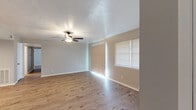 This single-story, 3-bedroom, 2-bathroom home offers a practical and comfortable layout designed to maximize every square foot. Throughout the home, warm wood-look laminate flooring creates a cohesive and inviting atmosphere, complemented by neutral-toned walls and clean white trim.

The living area is bright and open, featuring a ceiling fan with light fixture, textured ceiling, and multiple windows dressed with horizontal blinds that allow ample natural light to fill the space. The kitchen is thoughtfully designed with gray shaker-style cabinetry, granite-look countertops, a double stainless steel sink, and an electric range, offering a clean and modern aesthetic.

The spacious primary bedroom provides generous room for furnishings and includes its own ceiling fan. The additional bedrooms are well-sized, each featuring ceiling fans, natural light from windows, and hardwood-look flooring. One bedroom includes a built-in closet with sliding doors and shelving for organized storage.

Both bathrooms are finished with gray shaker vanity cabinets, granite-look countertops, and tiled tub-shower combinations. A hallway connects the bedrooms and living areas, with two closets offering additional storage throughout the home. The overall design is clean, modern, and move-in ready.