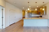 This single-floor residence is designed with a clean, contemporary aesthetic that balances functionality and comfort throughout. The open-concept kitchen and living area serves as the heart of the space, where light wood-tone flooring extends seamlessly underfoot. The kitchen is well-appointed with a full suite of stainless steel appliances, including a refrigerator, gas range, microwave, and dishwasher. Warm, wood-grain cabinetry lines the walls and provides generous storage, while a spacious peninsula topped with speckled granite countertops offers additional workspace and casual seating. Three pendant lights hang above the peninsula, complementing the recessed lighting overhead. The adjacent living area is open and airy, benefiting from natural light through large windows fitted with blinds.

The bedrooms feature plush carpeting and bright white walls, with windows that invite natural light and outdoor views. Double-door closets provide ample storage in the primary bedroom. The primary bathroom includes a dual-sink vanity with granite countertops, light wood cabinetry, a large mirror, and a walk-in shower, plus access to a walk-in closet. A second full bathroom offers a shower-tub combination. Five-panel white interior doors add a refined touch throughout the residence.