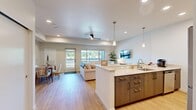 Located in Auburn, CA, this thoughtfully designed single-floor residence offers a seamless open-concept layout that integrates the kitchen, dining, and living areas into one cohesive, light-filled space. Light hardwood flooring flows throughout the main living areas, complemented by recessed lighting, pendant lights over the kitchen island, and a ceiling fan that enhance both function and ambiance.

The kitchen is a standout feature, boasting a large center island with a light stone countertop and sink, dark wood cabinetry, a stone tile backsplash, and stainless steel appliances including a range, refrigerator, and dishwasher. The adjacent dining area and living room benefit from large windows and a glass door that invite natural light and outdoor views.

The bedroom is a serene retreat, featuring plush carpeting, a generous window with outdoor views, and access to a spacious walk-in closet outfitted with multiple hanging rods and built-in shelving. Two additional closets provide ample storage throughout the unit.

The bathroom is cleanly finished with large-format tile flooring, a marble-topped vanity, and an accessible shower with grab bars. A dedicated laundry room houses a full-size washer and dryer with overhead cabinetry for added storage. The entrance and hallway complete this efficient, modern floor plan.