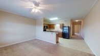 Located at 1805 8th Ave in Tuscaloosa, Alabama, this single-floor residence offers a well-organized layout with a seamless blend of functionality and comfort. The open-concept living and dining area is finished with plush carpeting and crown molding, and features a ceiling fan with light fixture. The space flows naturally into the kitchen, which is separated by a breakfast bar peninsula. The kitchen is outfitted with rich, warm-toned wooden cabinetry, granite-style laminate countertops, black appliances including a range, over-the-range microwave, refrigerator, and dishwasher, as well as a stainless steel sink. Tile flooring runs throughout the kitchen and entry areas. The bedrooms are generously sized, carpeted, and finished with neutral wall tones. One bedroom opens directly to a private outdoor patio through French doors, allowing natural light to fill the room. The bathroom features a rich wood vanity with a white countertop, a large wall mirror with overhead lighting, and clean tile flooring. Crown molding and ceiling fans are consistent design elements that lend a polished feel throughout the home. The overall ambiance is warm, practical, and move-in ready, suited for comfortable everyday living in a convenient Tuscaloosa location.