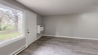 Located at 1200 Courtland Ave E in Kitchener, Ontario, this two-storey, 2-bedroom, 1-bathroom unit offers a practical and well-organized layout across two floors. The main level houses the majority of the living space, including a living room finished with light grey laminate flooring, neutral grey walls, and a window that allows natural light to filter in. A wall-mounted heating unit provides supplementary warmth in the living area. The galley-style kitchen features white cabinetry with wood-toned trim, tile backsplash, a double sink, and white appliances including a stove and refrigerator, all set on light laminate flooring. The full bathroom on this level includes a tiled tub-shower combination, a vanity with sink, and warm wood-toned flooring. Both bedrooms are finished with laminate flooring and neutral-toned walls. The spacious primary bedroom features a window with natural views and a baseboard heating unit, while the second bedroom includes a sliding double-door closet for convenient storage. Staircases connect the two levels, with the upper floor offering additional bedroom space. Throughout the unit, clean white trim and a consistent, understated color palette create a cohesive and functional living environment.