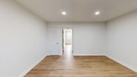 Located at 151 Normandy Hill Dr in Alexandria, VA, this two-bedroom, two-bathroom home is thoughtfully laid out across two floors. Warm, hardwood-style luxury vinyl flooring flows consistently throughout both levels, creating a cohesive and clean aesthetic anchored by bright white walls and crisp white trim.

The main floor houses the living room, kitchen, a hallway, and a staircase. The living room is bathed in natural light through a large window with blinds and features a front entry door with an adjacent window panel, while recessed lighting and a ceiling fan ensure year-round comfort. The galley-style kitchen is well-appointed with white shaker cabinetry, granite countertops, stainless steel appliances including a gas range, microwave, dishwasher, and refrigerator, all set above matching hardwood-style flooring.

Upstairs, the generously sized primary bedroom offers ample space and includes a louvered closet door and recessed lighting. The second bedroom features a bright window with natural views. Both bathrooms are finished with neutral tones; one features a soaking tub with a marble-look tile surround and brushed nickel fixtures, adding a refined touch. The two-floor layout provides a practical separation between living and sleeping areas, making this a well-organized and functional home.