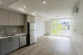 Located at 2650 Telegraph Ave in Berkeley, CA, this thoughtfully designed one-bedroom, one-bathroom unit offers a clean, modern aesthetic across a single floor. Light-toned hardwood flooring runs throughout the entire space, creating a cohesive and warm atmosphere.

The combined kitchen and living area forms the heart of the unit. The kitchen is outfitted with sleek flat-panel cabinetry in a soft gray-beige tone, a subway-tile backsplash, white quartz countertops, and a full suite of stainless steel appliances including a range, microwave, dishwasher, and refrigerator. Recessed lighting enhances the clean, contemporary feel.

A bright hallway connects the main living area to the private spaces, with a window at the end drawing in natural light and framing views of the surrounding greenery. The bedroom is a well-proportioned retreat featuring a dedicated closet with built-in hanging rods, neutral white walls, and a window overlooking the outdoors. An additional den provides flexible space suitable for a home office or guest area.

The bathroom features light hardwood-style flooring, a vanity with storage, a toilet, and a full bathtub with a sliding glass shower enclosure. Throughout the unit, the crisp white walls and abundant natural light contribute to an open, airy ambiance ideal for comfortable urban living.