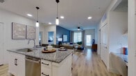 This well-designed single-floor residence offers two bedrooms and four bathrooms within a thoughtfully arranged open-concept floor plan. The kitchen serves as a central hub, featuring white shaker cabinetry with matte black hardware, granite countertops, stainless steel appliances including a French door refrigerator, and a large island with bar seating illuminated by pendant lighting. The kitchen flows seamlessly into the living area, which is anchored by a bold blue-gray accent wall, ceiling fan, and windows that bring in ample natural light.

The primary bedroom includes its own en-suite bathroom and a dedicated walk-in closet with built-in shelving and dual hanging rods. A bold navy accent wall adds visual depth to the primary suite. The en-suite bathroom features a dual-sink granite vanity, framed mirror, and modern lighting fixtures. The second bedroom is equally well-appointed, with a ceiling fan, natural light from a window, and direct access to its own bathroom featuring a granite vanity and tub-shower combination. Light wood-tone flooring runs consistently throughout, complementing the clean white walls and creating a cohesive, contemporary aesthetic across the entire residence.