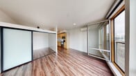 Located in the vibrant Capitol Hill neighborhood of Seattle, Unit 608 at 601 E Pike Street offers a thoughtfully designed single-floor layout that maximizes both function and style. Warm hardwood-style flooring flows throughout the entire unit, creating a cohesive and inviting atmosphere from room to room.

The open main living area is bright and airy, featuring clean white walls, recessed lighting, and a wall-mounted mini-split system for year-round climate control. A sleek glass sliding partition defines the bedroom space while maintaining an open, connected feel. The bedroom offers a quiet retreat with ample space and a modern glass-panel sliding door.

The kitchen is well-appointed with light natural wood cabinetry, gleaming stone-look countertops with subtle veining, a geometric tile backsplash, and stainless steel appliances including a range, microwave, and dishwasher. A deep single-basin sink with a contemporary pull-down faucet completes the space.

The bathroom is clean and functional, featuring a full soaking tub with shower, wood-look flooring, and crisp white finishes throughout. In-unit stacked laundry is conveniently tucked nearby. Large windows allow natural light to fill the unit, offering views of the dynamic Seattle streetscape below.
