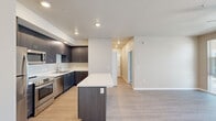 This thoughtfully designed one-bedroom, one-bathroom unit offers a functional and modern living experience across a single floor. The open-concept layout seamlessly connects the kitchen and living area, creating a spacious, airy feel enhanced by light hardwood-style flooring and neutral-toned walls throughout the common areas.

The kitchen is a standout feature, equipped with dark espresso cabinetry extending to the ceiling, white quartz countertops, stainless steel appliances including a range, microwave, dishwasher, and refrigerator, and a central island that provides additional prep space and storage. Recessed lighting adds a clean, modern touch.

The living area is bathed in natural light from large sliding glass doors that open onto a private balcony with exterior views. A ceiling fan overhead adds to the comfort of the space.

The bedroom features plush carpeting, a ceiling fan, and a sliding barn-style door that opens to a dedicated walk-in closet. The full bathroom includes a soaking tub, a dark-cabinetry vanity with storage drawers, and light wood-style flooring. A dedicated in-unit laundry closet houses a full-size side-by-side washer and dryer with built-in shelving above.