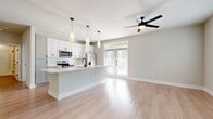 This two-story home offers a well-designed layout spread across two floors, with the main living areas on the ground floor and bedrooms above. The lower level centers around an open-concept kitchen and living room, creating a bright, connected space ideal for everyday living. The kitchen is outfitted with white shaker-style cabinetry featuring matte black hardware, stainless steel appliances including a side-by-side refrigerator, electric range, microwave, and dishwasher, and light granite countertops that extend to a functional island with a undermount sink. Pendant lighting and a ceiling fan complement the space, while French doors at the rear fill the area with natural light.

Light wood-tone flooring runs consistently throughout both floors, contributing to a clean, cohesive aesthetic. A staircase with wood treads leads to the upper level, where a hallway with recessed lighting connects the two bedrooms, a full bathroom, and two closets. The primary bedroom is generously sized with dual windows and a ceiling fan, while the secondary bedroom also features a window and ceiling fan. The shared bathroom includes a granite-topped vanity, tub-shower combination, and matte black fixtures, maintaining the consistent modern style found throughout the home.