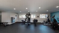 This well-equipped fitness center in Norwalk, CA offers a comprehensive workout environment spread across a single floor. The space is finished with durable rubber flooring throughout, providing both safety and functionality for a wide range of exercises. Recessed lighting and crown molding lend a clean, polished aesthetic to the interior, while multiple windows allow natural light to fill the space and offer views of the surrounding outdoor area.

The cardio zone is anchored by a bold teal accent wall and features multiple treadmills, elliptical trainers, and a stationary bike, with a wall-mounted television for entertainment during workouts. French doors in this area open directly to an outdoor space, enhancing ventilation and accessibility.

The strength training area includes a multi-functional cable machine, adjustable benches, and a rowing machine, providing versatile options for resistance training. A full wall of mirrors expands the visual depth of the space and supports proper form during exercise.

Free weight stations include tiered dumbbell racks stocked with a range of weights, catering to users of all fitness levels. A water bottle filling station is conveniently located near the entrance. The overall ambiance is bright, functional, and well-maintained, making this fitness center a practical and inviting facility for daily use.
