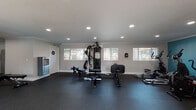 This well-equipped fitness center in Norwalk, CA offers a comprehensive workout environment spread across a single floor. The space is finished with durable rubber flooring throughout, providing both safety and functionality for a wide range of exercises. Recessed lighting and crown molding lend a clean, polished aesthetic to the interior, while multiple windows allow natural light to fill the space and offer views of the surrounding outdoor area.

The cardio zone is anchored by a bold teal accent wall and features multiple treadmills, elliptical trainers, and a stationary bike, with a wall-mounted television for entertainment during workouts. French doors in this area open directly to an outdoor space, enhancing ventilation and accessibility.

The strength training area includes a multi-functional cable machine, adjustable benches, and a rowing machine, providing versatile options for resistance training. A full wall of mirrors expands the visual depth of the space and supports proper form during exercise.

Free weight stations include tiered dumbbell racks stocked with a range of weights, catering to users of all fitness levels. A water bottle filling station is conveniently located near the entrance. The overall ambiance is bright, functional, and well-maintained, making this fitness center a practical and inviting facility for daily use.