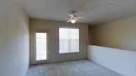 This single-story home in Keller, Texas offers a clean, functional layout with a warm and neutral aesthetic. The main living area is highlighted by soft, light-toned carpeting and beige walls that create a welcoming atmosphere. Natural light flows generously into the space through a large window fitted with horizontal blinds, complemented by a glass-panel exterior door that further brightens the room while providing direct outdoor access. A ceiling fan with a built-in light fixture is centrally positioned overhead, ensuring year-round comfort and consistent air circulation. A half-wall partition adds a subtle architectural detail, gently defining areas within the open layout while maintaining a sense of spaciousness. The overall design is straightforward and move-in ready, with a neutral color palette that provides a versatile backdrop for a variety of interior styles. The single-floor layout offers convenient, accessible living throughout. Located in Keller, TX, this home benefits from its position within a well-regarded North Texas community known for its suburban character and quality amenities.