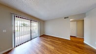 This single-floor residence offers a thoughtfully designed layout that balances functionality and comfort throughout. The living area makes a welcoming first impression with rich hardwood-style flooring, neutral-toned walls, and a textured ceiling. A large sliding glass door fitted with vertical blinds floods the space with natural light and provides direct access to an outdoor patio, while a secondary window near the front entry enhances the bright, airy feel.

The kitchen is efficiently arranged in a galley-style configuration, showcasing white cabinetry, light countertops, a subway tile backsplash, and a full suite of stainless steel appliances including a refrigerator, electric range, over-the-range microwave, and dishwasher. A peninsula with a double stainless steel sink extends into the adjoining area, offering additional prep space and a natural transition into the main living zone. Conveniently tucked just off the kitchen behind bi-fold doors is an in-unit laundry area with a full-size washer and dryer.

The bedroom is carpeted for comfort and features a ceiling fan, a window with blinds, and a door providing direct outdoor access, lending the room a versatile and well-ventilated character. The bathroom is clean and classic, outfitted with a tub-shower combination, a white vanity, and hardwood-style flooring that ties back to the rest of the home's design palette.