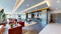 Located at 4015 Aspen Grove Dr in Franklin, TN, this generously sized single-floor amenity space offers a thoughtfully designed collection of recreational and social areas spanning a substantial footprint. The layout flows seamlessly across distinct zones, each finished with striking herringbone-patterned wood flooring that anchors the modern aesthetic throughout.

The centerpiece of the space is a full indoor putting green, bathed in natural light from expansive floor-to-ceiling windows that frame outdoor views of the surrounding community. Adjacent to the green, a regulation billiards table sits beneath elegant gold-accented pendant chandeliers, adding a refined touch to the recreational area. A dedicated bar seating section features high-top tables, bar stools, and patterned accent wall panels with built-in shelving, creating an ideal social hub.

The welcoming lobby lounge is appointed with bold terracotta-hued seating, lush tropical plants, and large sliding glass doors opening to an outdoor patio. Tray ceilings with warm indirect lighting add architectural depth throughout. A separate co-working room provides a quieter retreat with desk workstations, ergonomic seating, and a wall-mounted display. A media lounge with a large flat-screen TV and plush sectional seating rounds out the space, offering a comfortable environment for relaxation. The entry corridor features large-format tile flooring and double doors for easy access.