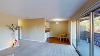 Located at 111 N Rengstorff Ave in Mountain View, California, this single-floor residence offers a functional and well-appointed layout throughout. The open living and dining area is finished with plush carpet in the living space and warm hardwood-style flooring in the dining zone, creating a clear distinction between the two areas. A pendant light fixture anchors the dining space, which is positioned alongside sliding glass doors that lead to an outdoor balcony, filling the area with natural light and views of surrounding greenery. The galley-style kitchen is efficiently designed with white cabinetry, dark granite countertops, stainless steel appliances including a range, microwave, and dishwasher, and hardwood-style flooring that ties seamlessly into the dining area. Two bedrooms are carpeted and finished with neutral-toned walls, offering a calm and restful atmosphere. Each room benefits from window access to natural light. The bathroom features a white vanity with dark granite countertops and an undermount sink, complemented by a large mirror and textured wall finish. Throughout the residence, a consistent neutral color palette and clean lines contribute to a cohesive and comfortable living environment.