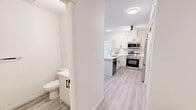 Located on the 7th floor at 310 Fifth Street SW in the heart of Calgary's downtown core, this 2-bedroom, 3-bathroom unit delivers a clean, modern aesthetic with a highly functional layout. Light-toned hardwood flooring flows seamlessly throughout, unifying the space with a bright, contemporary feel.

The living room is a standout, featuring expansive floor-to-ceiling windows that frame impressive views of Calgary's urban skyline, flooding the room with natural light. The kitchen is well-appointed with white shaker cabinetry, black hardware accents, a marble-style tile backsplash, a large white quartz waterfall island with bar seating, and a full suite of stainless steel appliances including a range, microwave, and refrigerator.

The primary bedroom is generously sized and benefits from a large window overlooking the city, while the second bedroom also enjoys direct skyline views. Both rooms offer a calm, neutral palette. The unit includes three bathrooms: a full bath with a glass-enclosed shower, a second full bath, and a convenient powder room — all finished in a crisp white palette with light wood-look flooring and black hardware details.

A well-proportioned hallway with sliding-door closet storage connects the living areas to the bedrooms, completing this efficiently designed urban residence.