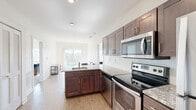 Located at 16790 Chandler Rd in East Lansing, Michigan, this 2-bedroom, 2-bathroom unit offers a well-organized single-floor layout designed for comfortable everyday living. The open-concept kitchen and living area serves as the heart of the home, where light hardwood-style flooring, neutral walls, and natural light from a large sliding glass door create a bright, airy atmosphere. The sliding door opens to a balcony with pleasant outdoor views of the surrounding greenery. The kitchen is equipped with stainless steel appliances — including a refrigerator, electric range, microwave, and dishwasher — complemented by rich dark-wood cabinetry, granite countertops with a subway tile backsplash, and a peninsula with bar seating for two. Both bedrooms feature plush carpeting, windows that invite natural light, and dedicated closets. The primary bedroom offers a comfortable, well-proportioned space. Each of the two bathrooms is finished with wood-look tile flooring, a granite-topped dark vanity, and a full tub/shower combination, maintaining a clean and cohesive aesthetic throughout. The overall design is modern and understated, with consistent finishes that give the entire unit a polished, move-in-ready feel.