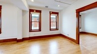 Located at 1701 Milton Ave in Solvay, NY, this well-appointed one-bedroom, two-bathroom unit blends classic architectural character with modern upgrades throughout its efficiently designed single-floor layout. Gleaming hardwood floors and rich, dark-stained wood trim and baseboards run consistently throughout the space, lending warmth and cohesion to every room. Multiple double-hung windows with distinctive wood surrounds flood the living areas with natural light and offer views of the surrounding neighborhood streetscape. The kitchen is a standout feature, outfitted with soft gray shaker cabinetry, white quartz countertops, a subway tile backsplash, and a full suite of stainless steel appliances including a French door refrigerator, range, and microwave. A central island with a black-accented sink and pendant lighting above adds both functionality and style. The bedroom is comfortably sized with dual windows and recessed lighting. The bathrooms are elegantly finished, featuring classic black-and-white mosaic tile floors, brass fixtures, a teal vanity with a round mirror, and a tiled shower with bold black accent bands. A dedicated laundry area houses a modern GE Profile all-in-one washer unit, completing this move-in-ready home.