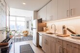 Located at 348 Baldwin Ave in Jersey City, NJ, this single-floor residence offers a bright, modern living experience with a thoughtfully designed open layout. The living area is the centerpiece of the home, bathed in natural light streaming through expansive floor-to-ceiling windows that frame sweeping views of the surrounding Jersey City neighborhood and the New York City skyline beyond. Light hardwood flooring runs throughout, complementing the clean, neutral palette and contemporary décor.

The galley-style kitchen is efficiently laid out with warm wood cabinetry, light quartz countertops, a classic tile backsplash, and a full suite of stainless steel appliances, including a refrigerator, dishwasher, and range. Under-cabinet lighting adds a polished finishing touch.

The living space flows seamlessly, offering room for both lounging and dining, with the dramatic cityscape serving as a constant backdrop. A stacked in-unit washer and dryer adds everyday convenience.

The bathroom is clean and refined, featuring large-format neutral tiles lining the soaking tub surround, light tile flooring, and crisp white walls that create a calm, spa-like atmosphere. Throughout the residence, the interplay of natural light, modern finishes, and urban views creates an inviting and sophisticated living environment.