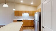 Located at 2205 Trellis Ridge Lane in De Pere, Wisconsin, this well-appointed 2-bedroom, 2-bathroom single-floor home offers a thoughtfully designed layout with a comfortable, functional flow throughout. The open kitchen and living area serves as the heart of the home, showcasing warm honey-toned cabinetry, white subway tile backsplash, light stone countertops, a kitchen island, and a full suite of stainless steel appliances including a refrigerator, range, microwave, and dishwasher. A pendant light adds a polished finishing touch. The living room features durable hardwood-style flooring, vaulted ceilings, a ceiling fan, baseboard heating, a wall-unit air conditioner, and a private exterior door that floods the space with natural light. The generously sized primary bedroom includes plush carpeting and direct access to a full bathroom, which connects to a walk-in closet with wire shelving. The second bedroom also features carpet and a double-door closet for ample storage. A second full bathroom with wood-toned vanity cabinetry and stone countertops serves the hallway. A dedicated in-unit laundry room complete with full-size washer and dryer adds everyday convenience. Neutral warm-beige tones and clean finishes create a cohesive, move-in-ready atmosphere throughout.