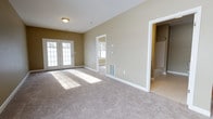 Located at 526 Middletown Rd in Hummelstown, PA, this single-floor space offers a clean, move-in-ready layout designed with functionality and comfort in mind. The main living area is generously proportioned, featuring plush wall-to-wall carpeting in a neutral tone that complements the warm beige walls and crisp white trim throughout. A set of French doors serves as a standout architectural feature, allowing abundant natural light to pour into the space while providing an elegant connection to the outdoors. An additional window in the adjoining room further enhances the bright, airy atmosphere. The open layout flows naturally between spaces, with doorways leading to what appears to be a additional room and a spacious closet or storage area, suggesting versatile usage options. Flush-mounted ceiling lighting and floor-level HVAC vents reflect a practical, well-considered design. The neutral color palette, white baseboards, and consistent finishes create a cohesive and welcoming ambiance throughout. The overall feel of the space is clean, bright, and adaptable, making it well-suited for a variety of occupants and furnishing styles.