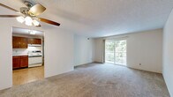 This well-laid-out two-bedroom, two-bathroom residence in Cincinnati, Ohio offers a comfortable and functional single-floor layout. The living room is generously sized, featuring plush carpeting, a ceiling fan with light fixture, and a large sliding glass door that opens to a balcony overlooking lush greenery, filling the space with natural light and outdoor views. The kitchen is equipped with warm oak cabinetry, ample counter space, and hardwood-style flooring, providing a practical and inviting cooking environment. The primary bedroom is a spacious retreat with carpet flooring, natural light from a window, and direct access to both a private bathroom and a dedicated walk-in closet outfitted with wire shelving for organized storage. The second bedroom also features carpet flooring, a window with garden views, and a sliding wood-panel closet door. Both bathrooms are clean and functional, with one featuring a full soaking tub and shower combination with chrome fixtures. Throughout the home, textured ceilings, warm-toned wood door frames, and neutral wall colors create a cohesive and inviting atmosphere.