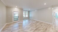 Located at 525 Ridge St in Charlottesville, VA, this thoughtfully designed 2-bedroom, 2-bathroom unit offers a modern aesthetic with high-quality finishes throughout. Light wood-look flooring flows seamlessly across the entire single-floor layout, complemented by soft neutral wall tones and recessed lighting that create a bright, welcoming atmosphere.

The open-concept kitchen and living area serves as the heart of the home. The kitchen is a standout, featuring bold navy cabinetry with brass hardware, a large center island with a warm wood base and white quartz countertop, a sleek stainless steel range with a wall-mounted hood, and eye-catching globe pendant lights. A textured tile backsplash and a distinctive navy entry door add personality to the space. The adjacent living area is bathed in natural light from large windows and a glass-paneled exterior door.

The bedrooms are well-proportioned, with the primary bedroom offering a stylish barn door as a design detail. Both bathrooms are finished with clean white tile and matte black fixtures, with one featuring a frameless glass walk-in shower. A dedicated laundry room includes a full-size washer and dryer with built-in shelving above. Crown molding and clean white trim throughout add a polished, cohesive finish to this well-appointed Charlottesville residence.