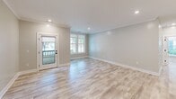 Located at 525 Ridge St in Charlottesville, VA, this thoughtfully designed 2-bedroom, 2-bathroom unit offers a modern aesthetic with high-quality finishes throughout. Light wood-look flooring flows seamlessly across the entire single-floor layout, complemented by soft neutral wall tones and recessed lighting that create a bright, welcoming atmosphere.

The open-concept kitchen and living area serves as the heart of the home. The kitchen is a standout, featuring bold navy cabinetry with brass hardware, a large center island with a warm wood base and white quartz countertop, a sleek stainless steel range with a wall-mounted hood, and eye-catching globe pendant lights. A textured tile backsplash and a distinctive navy entry door add personality to the space. The adjacent living area is bathed in natural light from large windows and a glass-paneled exterior door.

The bedrooms are well-proportioned, with the primary bedroom offering a stylish barn door as a design detail. Both bathrooms are finished with clean white tile and matte black fixtures, with one featuring a frameless glass walk-in shower. A dedicated laundry room includes a full-size washer and dryer with built-in shelving above. Crown molding and clean white trim throughout add a polished, cohesive finish to this well-appointed Charlottesville residence.
