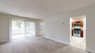 Located at 1100 West Chester Pike in West Chester, PA, this two-floor residence offers a practical and comfortable layout across two levels. The main floor centers around a spacious, carpeted living room filled with natural light from a large sliding glass door fitted with vertical blinds, providing a direct view of the greenery outside. A dedicated entry door adds convenience and security. Adjacent to the living area, the kitchen is efficiently designed with rich, warm-toned cabinetry, granite-look countertops, tile flooring, and stainless steel appliances including an electric range, built-in microwave, and dishwasher — all illuminated by recessed ceiling lighting. A staircase with a classic wood banister and carpeted treads connects the two floors, leading to the upper level where a generously sized carpeted bedroom with a baseboard heating unit provides a quiet retreat. The bathroom features tile flooring, a white vanity, an over-toilet storage cabinet, and brushed nickel fixtures. A dedicated in-unit laundry area houses a stacked washer and dryer alongside shelving, adding everyday convenience. Throughout, neutral tones and clean finishes create a consistent, move-in-ready aesthetic.