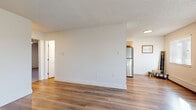 This single-floor, 2-bedroom, 1-bathroom residence in Thornton, Colorado offers a practical and comfortable layout designed for efficient everyday living. The main living area features warm wood-style flooring, neutral white walls, and a textured ceiling, with natural light streaming in through sizable windows fitted with blinds. Baseboard heating runs throughout, ensuring consistent warmth across the home.

The kitchen is well-appointed with light natural wood cabinetry, dark countertops, and a full suite of stainless steel appliances, including a refrigerator, range, and microwave. The wood-style flooring continues seamlessly into this space, adding cohesion to the open layout.

Both bedrooms are carpeted in a neutral gray tone and include ceiling fans with light fixtures. The primary bedroom offers a generous footprint with a sliding-door closet providing dedicated storage. The second bedroom also features a window with blinds and baseboard heating. An additional closet is accessible from the hallway, adding to the overall storage options.

The bathroom features a wood-toned vanity with a gray countertop, an oval sink, and a large mirror, finished with hardwood-style flooring that ties back to the rest of the home. A connecting hallway links all rooms efficiently, completing this clean and functional floor plan.
