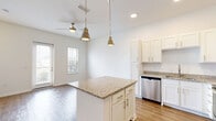 Located at 9105 Tredinick Pkwy in Jacksonville, FL, this two-story home offers a well-planned layout across two floors. The main level welcomes you through a dedicated entrance that opens into a bright, open-concept living area where the living room, dining room, and kitchen flow seamlessly together. The kitchen is a standout feature, showcasing white shaker cabinetry, granite countertops, a central island with pendant lighting, and a full suite of stainless steel appliances. Wood-look flooring and a ceiling fan complete the main living space, which benefits from natural light through multiple windows and door access to the exterior. A garage and laundry area add everyday convenience on this floor.

Upstairs, two bedrooms are complemented by plush carpeting, ceiling fans, and natural light from well-positioned windows. The generously sized primary bedroom includes a walk-in closet with built-in shelving. Three bathrooms throughout the home feature granite-topped vanities with white cabinetry and wood-look flooring. A hallway and additional closet space provide practical storage. The property sits within a neatly maintained community with landscaped grounds and an iron perimeter fence.