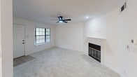 This well-designed one-bedroom, one-bathroom unit in Shreveport, Louisiana offers a clean, modern aesthetic throughout its efficiently laid-out single floor. The open kitchen and living area serves as the heart of the home, where the kitchen impresses with crisp white shaker cabinets, black hardware accents, white quartz countertops, a stainless steel sink, and black appliances including a refrigerator, range, and built-in microwave. Light wood-look flooring anchors the kitchen, while a stylish chandelier adds an elegant touch overhead. The living room flows naturally from the kitchen, featuring soft carpet, a ceiling fan, recessed lighting, a classic fireplace with a white mantle, and a window that brings in natural light. The generously sized bedroom offers plush carpeting, dual closet units, a modern ceiling fan, and a door with blinds providing additional access and natural light. The bathroom is thoughtfully updated with a white vanity, quartz countertop, black fixtures, a framed mirror, additional cabinetry for storage, and a full tub-shower combination. The entryway features a large window, filling the space with warmth and light from the moment you step inside.