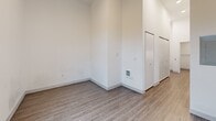 Located at 5230 39th Ave S in Seattle's Brighton neighborhood, this efficiently designed studio unit offers a thoughtful layout that maximizes every square foot. The main living area is bright and open, featuring warm wood-look luxury vinyl plank flooring, crisp white walls, and tall windows with a glass-paned door that invite natural light and provide views of the surrounding outdoor space. The generous ceiling height enhances the sense of openness throughout.

The kitchen is neatly tucked into its own alcove and is well-appointed with dark wood cabinetry, stainless steel appliances including a range, over-the-range microwave, and refrigerator, complemented by a tile backsplash and ample upper and lower cabinet storage.

The bathroom is clean and contemporary, featuring a full soaking tub with a tiled shower surround, a dark wood vanity with a white countertop and undermount sink, and coordinating wood-look flooring that ties the space together. Additional features include a built-in electrical panel, a wall-mounted climate control unit, and generous closet storage. The unit's modern, minimalist design makes it a functional and stylish living space.