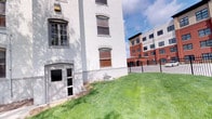Situated at 1030 N. College in Indianapolis, Indiana, this space occupies a single floor within a distinguished white-painted brick building that exudes historic architectural charm. The building's exterior showcases classic arched and rectangular multi-pane windows, contributing to its enduring character and visual appeal. The structure's solid masonry construction speaks to its age and durability, while the painted brick exterior gives it a clean, refined appearance.

The property is set on a well-maintained green lawn that gently slopes along the building's perimeter, adding a touch of natural softness to the urban setting. A metal entry door provides access at ground level, complemented by wrought iron fencing that defines the property boundary. The surrounding neighborhood reflects a dynamic urban environment, with neighboring modern mixed-use and multi-story buildings visible nearby, highlighting the contrast between historic and contemporary Indianapolis architecture.

The location along N. College Avenue places this space within a vibrant Indianapolis corridor, offering convenient access to the amenities and energy of the city. The combination of historic architectural detailing, brick craftsmanship, and a well-kept exterior landscape makes this a distinctive and characterful space within its urban context.