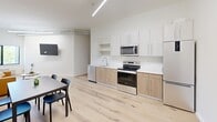 Located at 440 Monroe Ave in Memphis, TN, this single-floor unit offers a thoughtfully designed layout that maximizes every square foot. Light hardwood flooring flows throughout the entire space, lending warmth and continuity to the modern aesthetic.

The open-concept kitchen and living area serves as the heart of the unit. The kitchen features two-tone cabinetry — warm wood lower cabinets paired with white upper cabinets — complemented by a white quartz countertop, undermount sink, and a full suite of stainless steel appliances including a range, microwave, dishwasher, and refrigerator. Sleek linear LED lighting runs along the ceiling, adding a contemporary industrial touch alongside exposed conduit accents visible in the living area.

The living space is bright and airy, with soaring ceilings that enhance the sense of openness. A large window frames a view of surrounding greenery, allowing ample natural light to fill the room.

The bathroom is clean and minimal, featuring a tiled tub-shower combination, hardwood flooring, and crisp white fixtures. A dedicated laundry area houses a stacked Whirlpool washer and dryer unit, providing added convenience. A hallway connects the spaces efficiently, completing this well-appointed, modern residence in the heart of Memphis.
