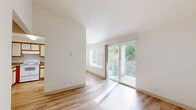 This single-floor, one-bedroom, one-bathroom residence offers a thoughtfully arranged layout that maximizes its comfortable footprint. The bright living room is a standout feature, bathed in natural light from large windows and a sliding glass door that opens onto a private balcony overlooking a vibrant, tree-lined landscape. Light wood-style flooring runs throughout the main living areas, adding warmth and continuity to the space.

The kitchen is efficiently designed in a U-shaped configuration, featuring white cabinetry with warm wood trim accents, a full suite of white appliances including a refrigerator, range, and dishwasher, and a countertop peninsula that connects seamlessly to the dining area. A skylight-style overhead fixture keeps the kitchen well-lit.

The spacious primary bedroom is carpeted for comfort and includes two closets with warm wood-toned bifold doors, offering generous storage. A window frames views of the surrounding greenery, filling the room with natural light.

The full bathroom features light wood-style flooring, a shower/tub combination, vanity with wood-trimmed cabinetry, and a mirrored medicine cabinet. A dedicated laundry room houses a full-size, side-by-side washer and dryer with overhead shelving for added convenience. A hallway and two closets round out this well-organized and functional residence.