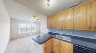 This 460 square foot single-floor apartment offers a well-designed living space that maximizes efficiency and comfort. The heart of the home is a modern kitchen, featuring honey-colored wooden cabinets that provide ample storage. Stainless steel appliances, including a refrigerator, built-in microwave, and electric range, add a contemporary touch. The kitchen's L-shaped layout incorporates a dark countertop that extends to form a convenient breakfast bar, delineating the cooking area from the living space.

The 130 square foot primary bedroom is generously sized for the apartment's overall dimensions. It boasts plush carpeting and is illuminated by natural light from a sliding glass door leading to a private balcony. An elegant crystal chandelier adds a touch of sophistication to the room. The bedroom also features a closet for storage.

Throughout the apartment, a combination of materials creates visual interest: wood-look laminate flooring in the kitchen transitions to carpet in the living areas and bedroom. The neutral color palette of whites and beiges on the walls allows for personal decorating styles. The apartment's layout includes a bathroom and additional closet space, ensuring practical living in a compact footprint. Large windows and the balcony offer views of the surrounding area, enhancing the sense of space in this efficiently designed apartment.