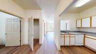 Located at 1040 E 33rd St in Baltimore, MD, this two-bedroom, two-bathroom residence offers a well-organized single-level layout with a clean, neutral design throughout. The interior features warm hardwood-style flooring in the main living and kitchen areas, creating a cohesive flow through the space.

The kitchen is equipped with white cabinetry accented by wood-tone trim, gray laminate countertops, and a full suite of white appliances including an electric range, refrigerator, and dishwasher. A hallway connects the kitchen to the main living area, with a walk-in closet conveniently situated along the corridor.

Both bedrooms are carpeted and receive natural light through large windows fitted with horizontal blinds. The spacious primary bedroom includes a private en-suite bathroom and direct access to an additional closet. The second bedroom is well-proportioned and equally bright.

Each bathroom features a white vanity with a gray countertop, an overhead light fixture, a mirrored medicine cabinet, and a tiled tub-shower combination with stainless steel grab bars. The hardwood-style flooring continues into the bathrooms, adding consistency to the overall aesthetic.

The layout is practical and efficient, making effective use of the available space while maintaining a light, airy atmosphere throughout.