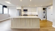 This thoughtfully updated one-bedroom, one-bathroom unit in Brampton, Ontario offers a clean, modern aesthetic throughout. Light wood laminate flooring runs continuously across the open-plan layout, creating a warm and cohesive feel from room to room. The entryway hallway leads seamlessly into the combined kitchen and living area, where an abundance of natural light pours in through expansive floor-to-ceiling windows that frame panoramic views of the surrounding cityscape.

The kitchen is a standout feature, outfitted with high-gloss white upper cabinetry, light wood lower cabinets, and a generous island topped with a marble-effect white countertop. Stainless steel appliances — including a refrigerator, stove, and built-in microwave — complete the modern, functional space, all illuminated by recessed pot lighting.

The spacious living area benefits from wraparound corner windows that flood the room with natural light and offer sweeping outdoor views, creating an airy and open ambiance. The bedroom is a well-proportioned retreat featuring large windows with city views and a built-in sliding door closet. The bathroom is finished with crisp white tile, a marble-top vanity, and a full tub-shower combination, delivering a clean and polished look throughout.