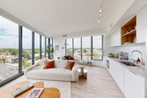 Located in Washington, DC's vibrant NoMa neighborhood, this contemporary 2-bedroom, 2-bathroom residence offers an impressive living experience defined by abundant natural light and panoramic city views. The open-concept living and dining area is anchored by dramatic floor-to-ceiling windows that wrap the corner of the space, flooding the interior with daylight and framing sweeping elevated views of the DC skyline and surrounding neighborhoods. Light hardwood flooring flows seamlessly throughout, complementing the clean white walls and modern aesthetic.

The sleek kitchen features white cabinetry, a smooth cooktop, stainless steel appliances including a Bosch oven, and a bright picture window that continues the view-forward design philosophy. A bright hallway with louvered closet doors connects the living areas to the private quarters, where both bedrooms maintain the home's minimalist character. The spacious primary bedroom boasts its own floor-to-ceiling windows with breathtaking elevated views of the city, creating a serene retreat. The second bedroom offers a built-in closet and easy hallway access.

Both bathrooms are thoughtfully finished, with one featuring hexagonal slate tile flooring, a soaking tub, vertical subway tile surround, and a warm wood vanity with an illuminated mirror. In-unit laundry adds convenience, completing this well-appointed urban residence.