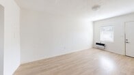 Located at 925 N Krome in Homestead, FL, this one-bedroom, one-bathroom unit offers a practical and efficient single-floor layout. Throughout the space, light wood-look flooring adds warmth and continuity, complemented by white textured walls and a classic textured ceiling.

The living room is an open, airy space featuring a wall-mounted AC unit and a window that brings in natural light, creating a bright and comfortable atmosphere. A hallway connects the main living areas to the private spaces of the unit.

The kitchen is thoughtfully appointed with warm-toned wood cabinetry, granite countertops, a stainless steel sink, and black appliances including an electric range and microwave. A window and exterior door provide additional natural light and convenient access.

The bedroom offers a comfortable footprint, enhanced by a ceiling fan, a window with blinds, and light flooring consistent with the rest of the unit. A dedicated closet provides practical storage.

The bathroom includes a full tub-shower combo with white tile surround, chrome fixtures, and a small window that allows for natural ventilation. A utility room rounds out the layout, adding functional storage and service space to this well-organized unit.