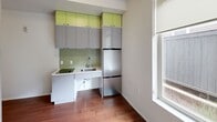 Located at 838 NE 69th St in Seattle's Roosevelt neighborhood, this efficiently designed studio unit makes smart use of every square foot across a single level. The open main area features rich hardwood flooring and crisp white walls that keep the space feeling bright and airy, complemented by a large window fitted with a roller shade that brings in natural light.

The kitchenette is thoughtfully appointed with gray cabinetry accented by vibrant lime-green upper cabinet faces, a mosaic tile backsplash, a stainless steel sink, a microwave, and a full-size stainless steel refrigerator-freezer — maximizing both function and style in a compact footprint. A built-in wall unit houses a fold-down Murphy bed alongside high-gloss white cabinetry with open lime-green shelving above, offering flexible living and sleeping arrangements without sacrificing storage.

The bathroom is finished with large-format white wall tiles, light tile flooring, and includes accessibility-friendly grab bars. A stacked washer and dryer unit is conveniently integrated into the bathroom, adding in-unit laundry to this well-considered layout. The overall design balances modern aesthetics with practical efficiency, making this an intelligently configured urban unit.