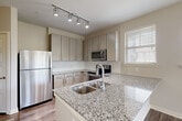 Located at 1111 Oakley Industrial Blvd in Fairburn, GA, this 2-bedroom, 3-bathroom single-floor residence offers a thoughtfully designed layout across a comfortable footprint. The kitchen serves as a central highlight, featuring granite countertops with an undermount sink, a peninsula island, light wood cabinetry, subway tile backsplash, stainless steel appliances, and track lighting overhead. Hardwood-style flooring flows through the main living and kitchen areas, while a wide open layout connects the kitchen seamlessly to the living space. A well-lit hallway leads to the bedrooms, each carpeted and equipped with ceiling fans and natural light from multiple windows. The primary bedroom offers a generous layout with its own en-suite bathroom and a walk-in closet outfitted with wire shelving systems. The bathrooms are finished with granite-topped vanities, tile flooring, and modern fixtures; one features a soaking tub with tiled surround and a dual-sink vanity. Two closets provide ample storage throughout the home. The interior palette of neutral tones, crisp white trim, and five-panel doors contributes to a clean, modern aesthetic throughout.