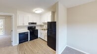 This single-floor residence on Pineview Lane in Gastonia, North Carolina, offers a practical and well-organized layout designed for comfortable everyday living. The kitchen is outfitted with white shaker-style cabinetry, a black appliance suite including a range, dishwasher, and refrigerator, and a double sink set against clean countertops. Wood-look flooring runs through the kitchen, transitioning to plush carpet in the main living areas.

The living area is generously proportioned, featuring a ceiling fan with a light fixture and a window that allows natural light to fill the space. A wall-unit HVAC system provides climate control. Adjacent to the living area, a dedicated entry nook functions as a mudroom, complete with built-in bench seating, open cubbies for storage, and a row of wall-mounted hooks—a practical organizational feature.

The bedroom is a comfortable, carpeted space with a ceiling fan, textured ceiling, and a sliding closet door providing ample storage. The bathroom includes a single-sink vanity with a framed mirror, light fixture above, and a full tub-shower combination with a white surround. Neutral tones and consistent finishes throughout contribute to a cohesive and move-in-ready ambiance.