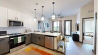 Located at 944 Broadcast Pl in Jacksonville, FL, this 1-bedroom, 1-bathroom residence offers a thoughtfully designed layout across a single floor. The open-concept kitchen and living area serves as the heart of the home, where light wood-style flooring flows throughout. The kitchen is outfitted with two-tone cabinetry — white upper cabinets paired with gray lower cabinets — white quartz countertops, a geometric tile backsplash, and a full suite of stainless steel appliances including a side-by-side refrigerator, gas range, microwave, and dishwasher. Pendant lighting over the peninsula adds a modern touch. The living area is bright and inviting, featuring large windows dressed with decorative curtains and a glass door leading to a private balcony overlooking green outdoor views. A ceiling fan enhances comfort. The spacious primary bedroom is carpeted and filled with natural light from a large window, complete with a ceiling fan. Two closets provide ample storage, including a well-organized walk-in with built-in shelving. The bathroom features a dual-sink vanity with gray cabinetry, white countertops, and a walk-in shower with striking black-framed glass doors and white tile surround. An in-unit laundry area completes this well-equipped residence.