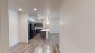 Located at 8855 N Casa Grande Hwy in Marana, AZ, this contemporary single-floor residence showcases a thoughtfully designed open-concept layout with clean, modern finishes throughout. The kitchen is a standout feature, boasting dark wood-toned cabinetry, a classic tile backsplash, black appliances including a full-size refrigerator, range, and microwave, and a generous island with a crisp white countertop and undermount sink. Stylish pendant lighting and a track light system illuminate the space with a warm, functional glow. Wood-look flooring extends seamlessly through the kitchen and living area, which is bright and open, benefiting from large sliding glass doors that invite natural light and provide outdoor access. The bedroom features plush carpeting, a ceiling fan, and windows with blinds, offering a comfortable and private retreat with convenient access to a private exterior door. The bathroom is finished with dark cabinetry, white countertops, a wide vanity mirror with contemporary bar lighting, and a full tub-shower combination. The overall ambiance is clean, contemporary, and move-in ready, reflecting a cohesive modern aesthetic throughout the entire space.
