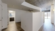 Located on the 14th floor at 803 S Hope St in the heart of Downtown Los Angeles, this unit offers a compelling blend of contemporary design and urban functionality. The living room is the architectural centerpiece, featuring dramatic floor-to-ceiling windows that frame sweeping panoramic views of the Downtown LA skyline. Exposed concrete ceiling details contrast with crisp white walls and light-toned hardwood-style flooring, lending the space an industrial-modern character. A ceiling fan enhances comfort while partial-height partition walls define zones within the open layout.

The kitchen is well-equipped with dark espresso cabinetry, stainless steel appliances including a refrigerator, range, microwave, and dishwasher, and light countertops. A glass door leads directly to a private balcony, providing additional city views and outdoor access. The hallway connects the living areas to the private zones efficiently, maintaining a logical flow throughout the unit.

The bathroom features a full soaking tub with a tiled surround in neutral tones, gray floor tiles, and clean white fixtures, delivering a functional and understated aesthetic. Overall, the unit presents a cohesive modern palette suited to urban living.