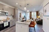 Located at 515 Royal Court in uptown Charlotte, NC, this two-bedroom, two-bathroom residence offers a thoughtfully designed open-concept layout with modern finishes throughout. The kitchen serves as a central hub of the home, featuring granite countertop surfaces, a large island with an undermount sink and bar seating, gray shaker-style cabinetry, subway tile backsplash, stainless steel appliances, and elegant pendant lighting overhead. Wood-style flooring flows seamlessly into the living room, which is filled with natural light from large windows and a glass door opening to a private balcony. Each bedroom is well-proportioned, with the primary suite offering ample closet storage via a walk-in closet equipped with wire shelving systems. Both bathrooms are finished with granite-topped dual vanities, gray cabinetry, black hardware accents, and tiled shower surrounds. The primary bath connects directly to the walk-in closet for added convenience. The second bedroom benefits from generous window coverage, bringing in abundant natural light and views of the surrounding greenery. Recessed lighting and ceiling fans contribute to the comfortable, contemporary ambiance found throughout this well-appointed Charlotte residence.