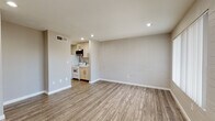 Located at 146 E Broadway Blvd in Tucson, Arizona, this single-floor unit offers a clean, modern aesthetic throughout. The open living area is defined by durable wood-look plank flooring and neutral-toned walls, with painted brick masonry accents adding a subtle textural element. Recessed lighting illuminates the space efficiently, contributing to a bright and welcoming atmosphere.

The compact kitchen is thoughtfully appointed with light wood cabinetry, a white electric range, a full-size refrigerator, a stainless steel over-the-range microwave, and a single-basin sink — providing all essential cooking amenities in an efficient layout.

The bedroom features continued wood-look flooring, a built-in closet with shelving, and direct access to the kitchen, supporting a practical flow throughout the unit. A glass-paneled entry door allows natural light to filter into the living space, enhancing the overall brightness.

The bathroom is finished with warm wood-tone flooring and floor-to-ceiling vertically tiled walls in a rich gray tone. It includes a walk-in shower with a rainfall showerhead, a toilet, and a clean, contemporary design sensibility. The unit's straightforward, modern finishes and efficient layout make it a functional and attractive space in the heart of Tucson.